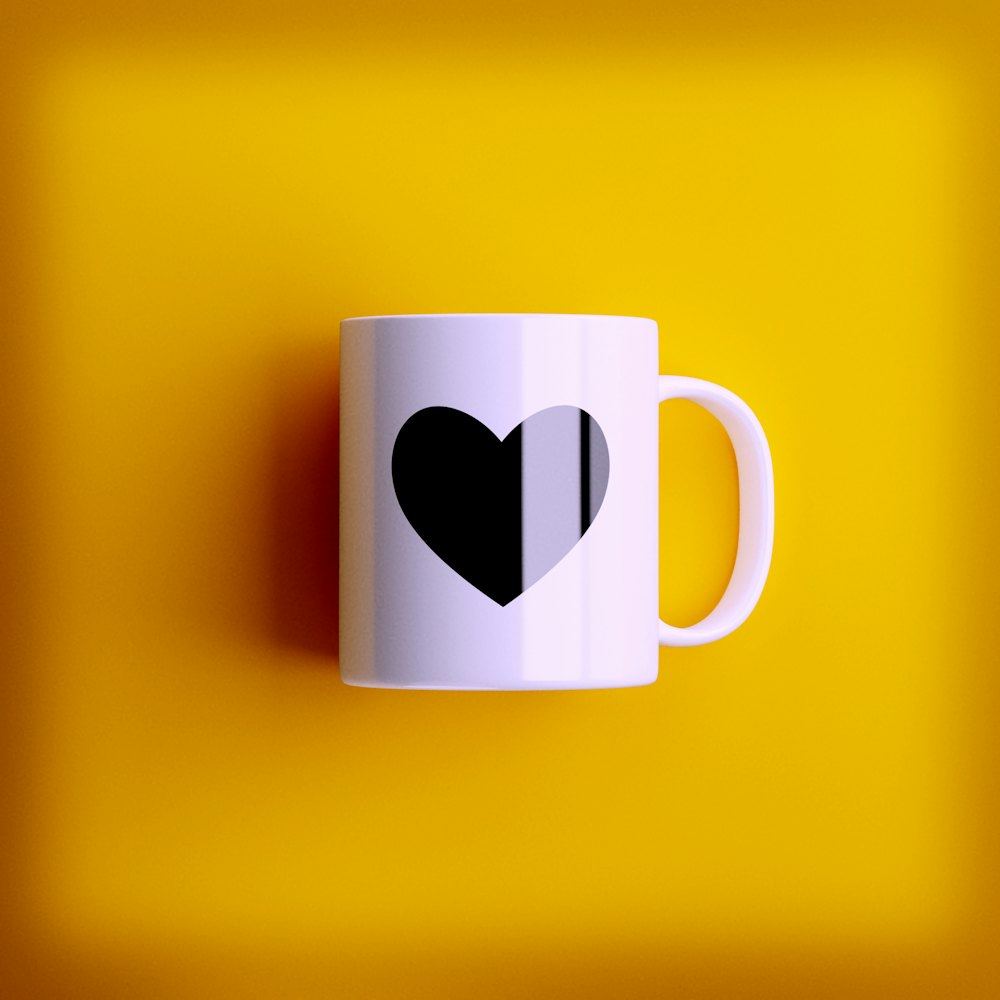 Caneca branca com coração estampado sobre fundo amarelo